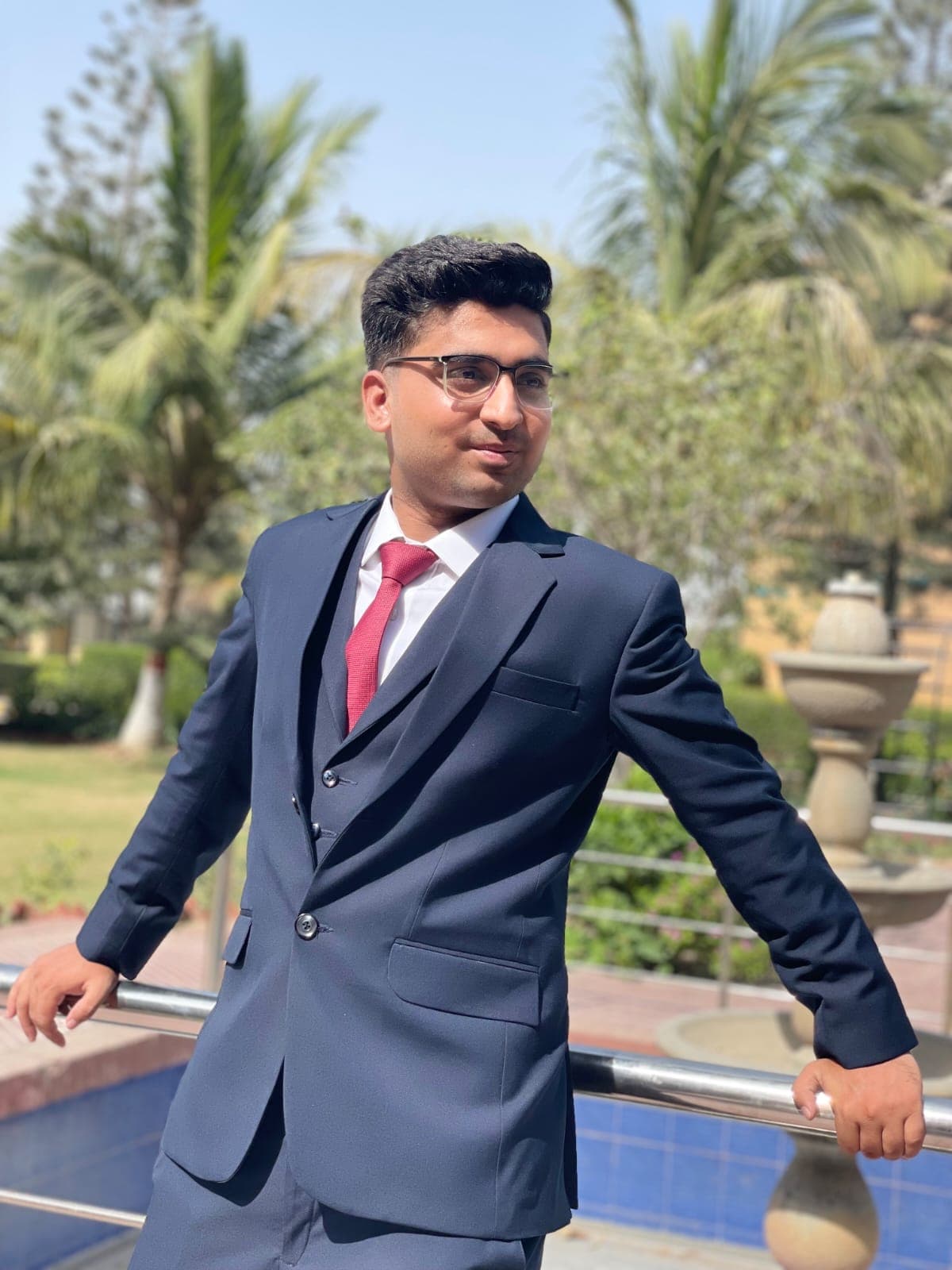 Muneeb Ur Rehman smiling, wearing glasses and a navy suit